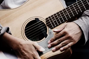 Hands resting on a guitar